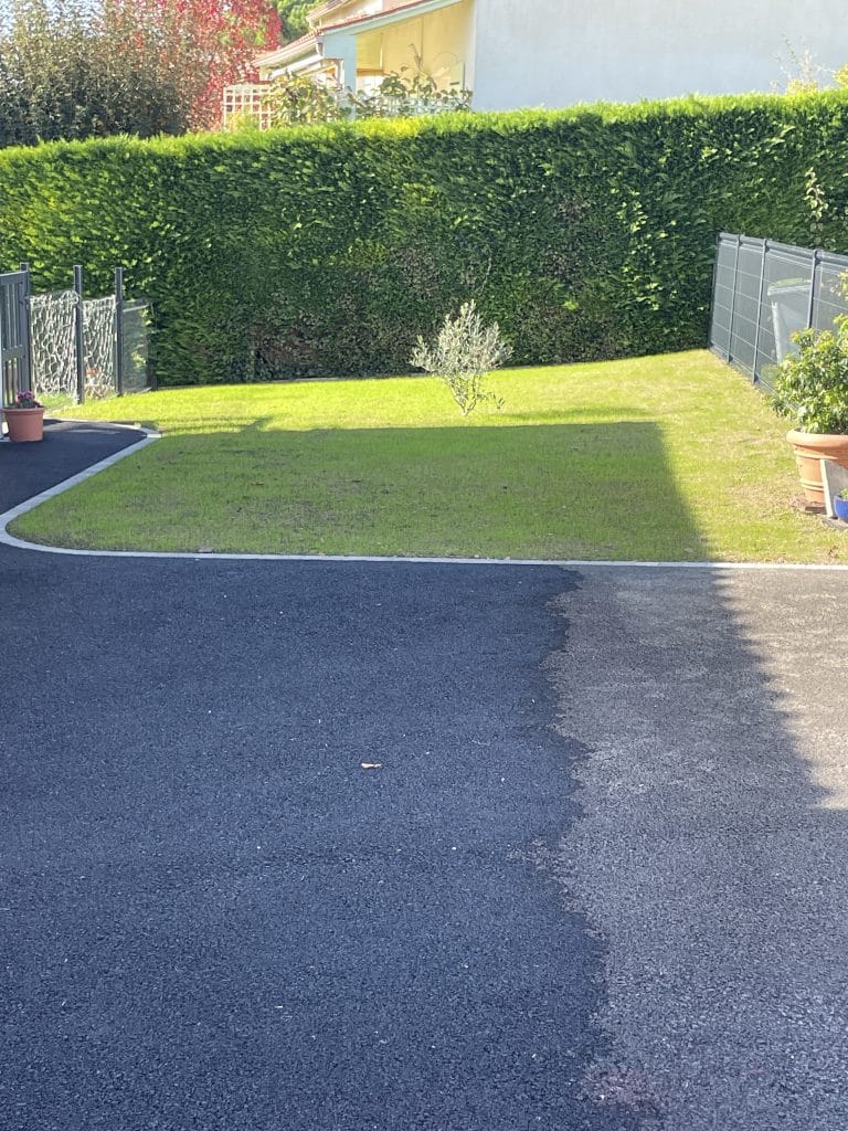 Aménagement extérieur avec zone engazonnée en bordure d’allée en enrobé, transition propre entre accès véhicule et jardin.