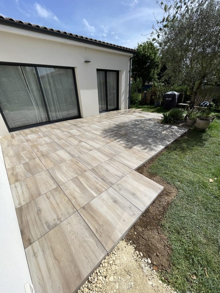 Terrasse en dalles effet bois aménagée devant une maison contemporaine, création d’un espace extérieur esthétique et fonctionnel.
